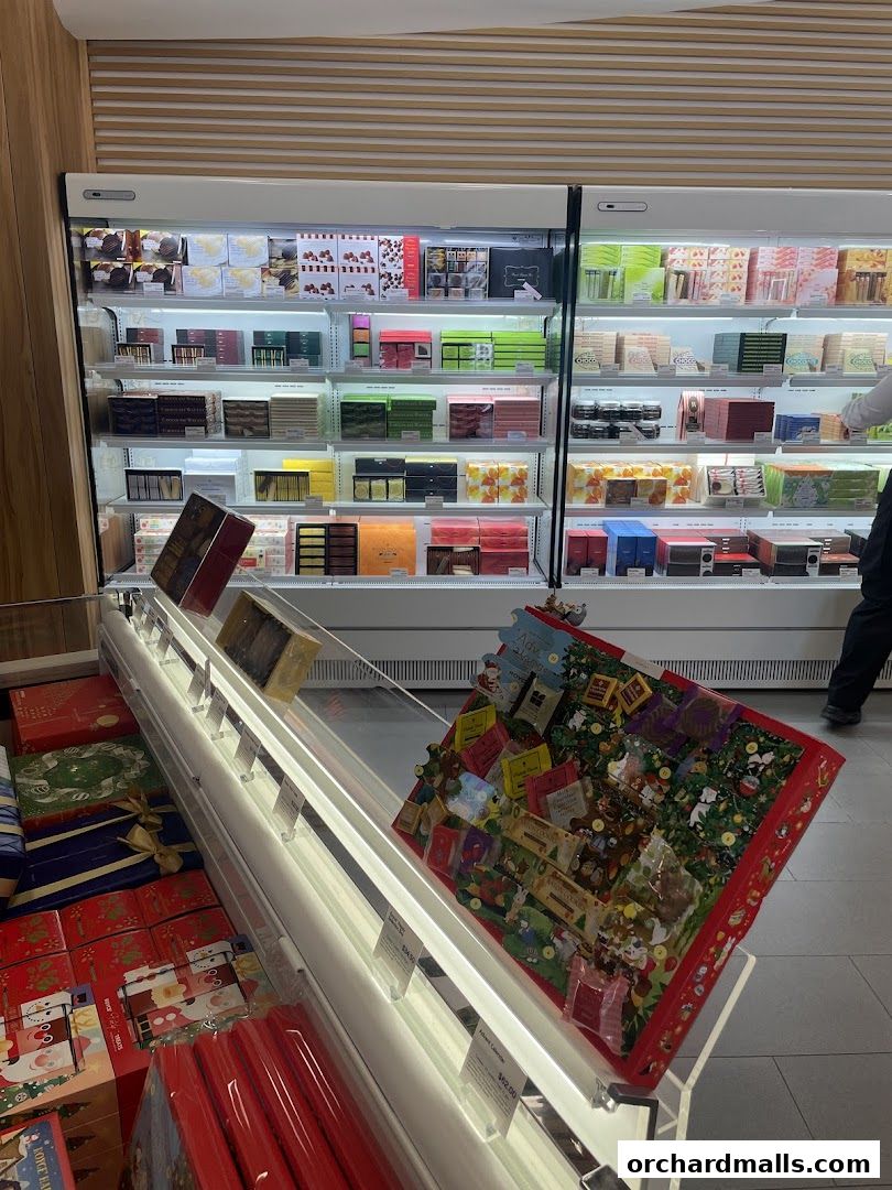 A display of beautifully packaged chocolates and confectionery in a well-lit retail setting.