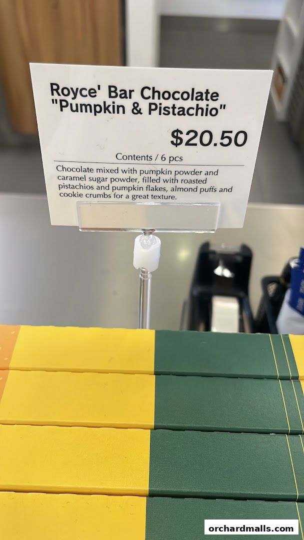 A sign displays Royce's "Pumpkin & Pistachio" bar chocolate with its price and description.