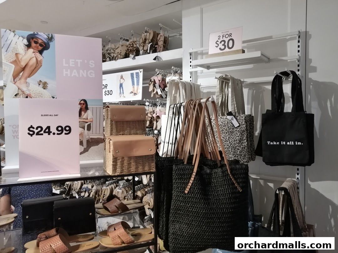 A retail display featuring sandals, tote bags, and promotional signage for Rubi Shoes.