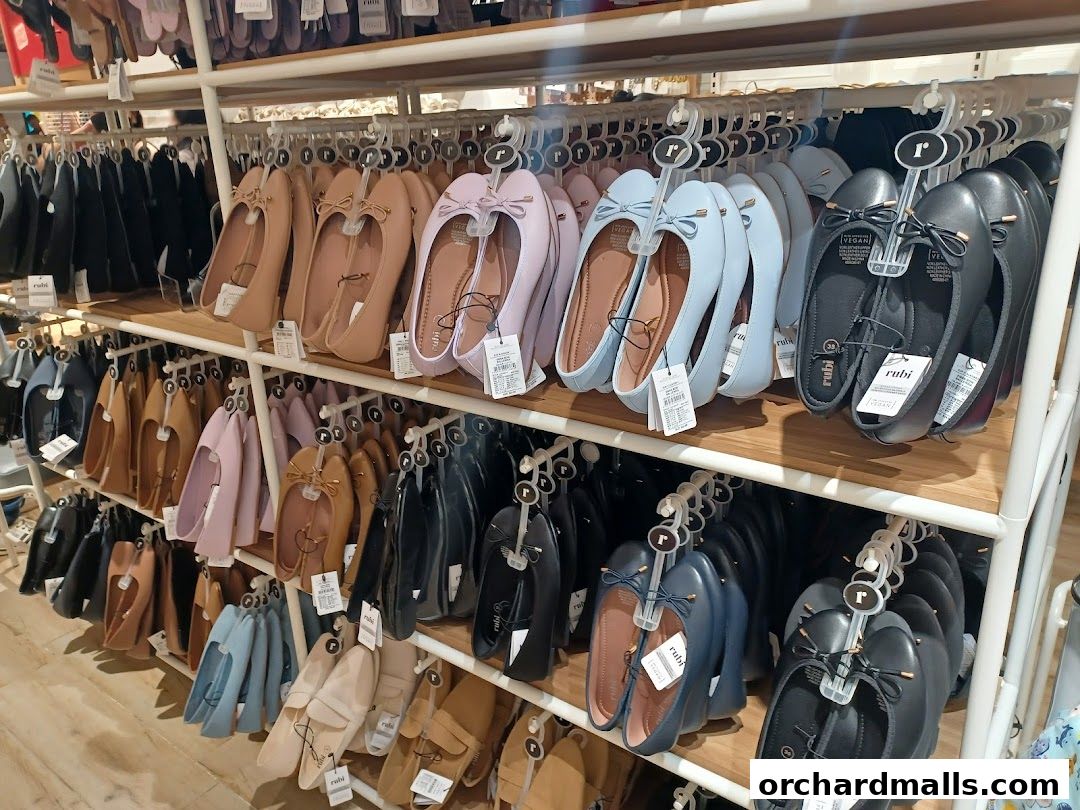 A display of various flat shoes in different colors, neatly arranged on shelves and hangers.