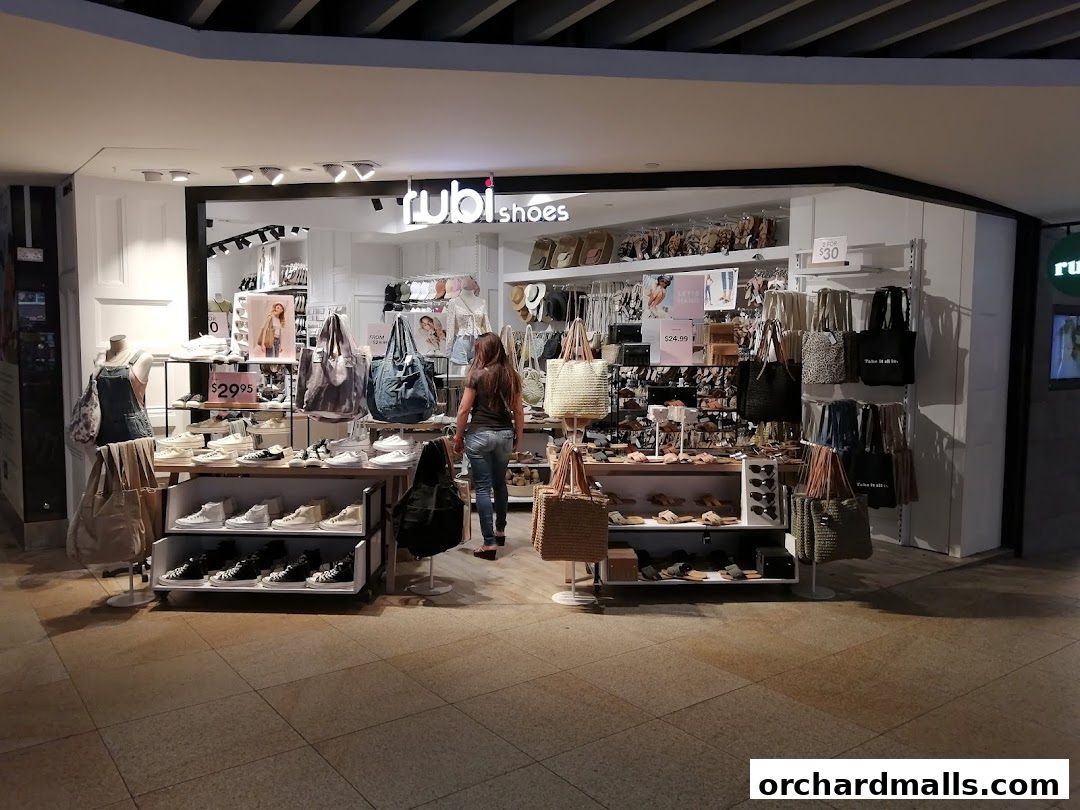 A Rubi Shoes store displaying various footwear and bags, with a customer browsing.