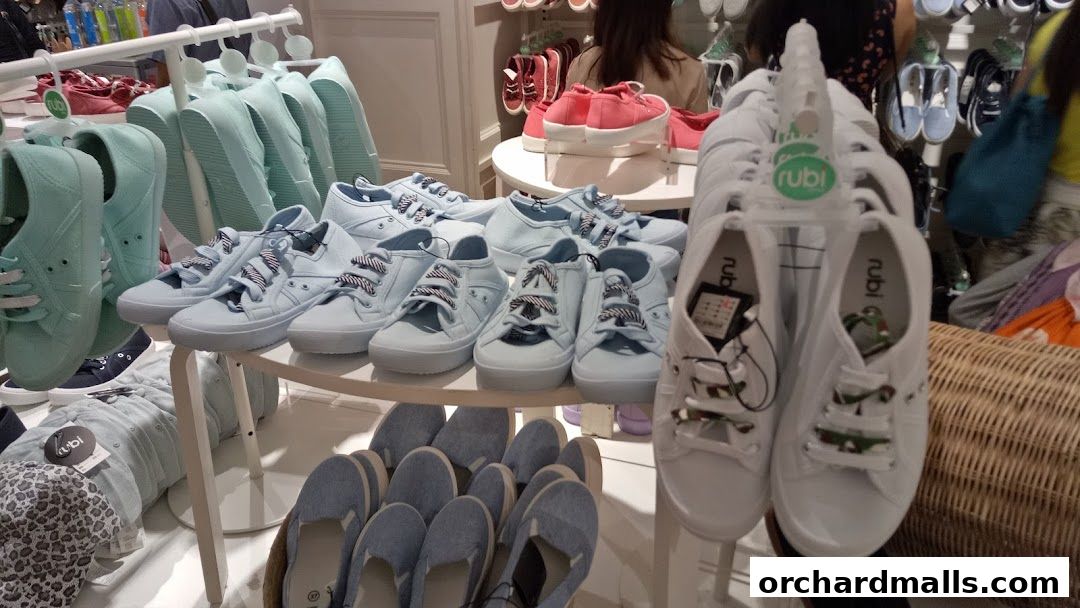 A display of various casual shoes, including sneakers and slip-ons, in pastel colors.