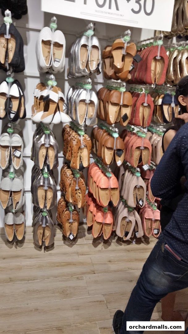 A wall display of various flat shoes in different colors and styles at Rubi Shoes.