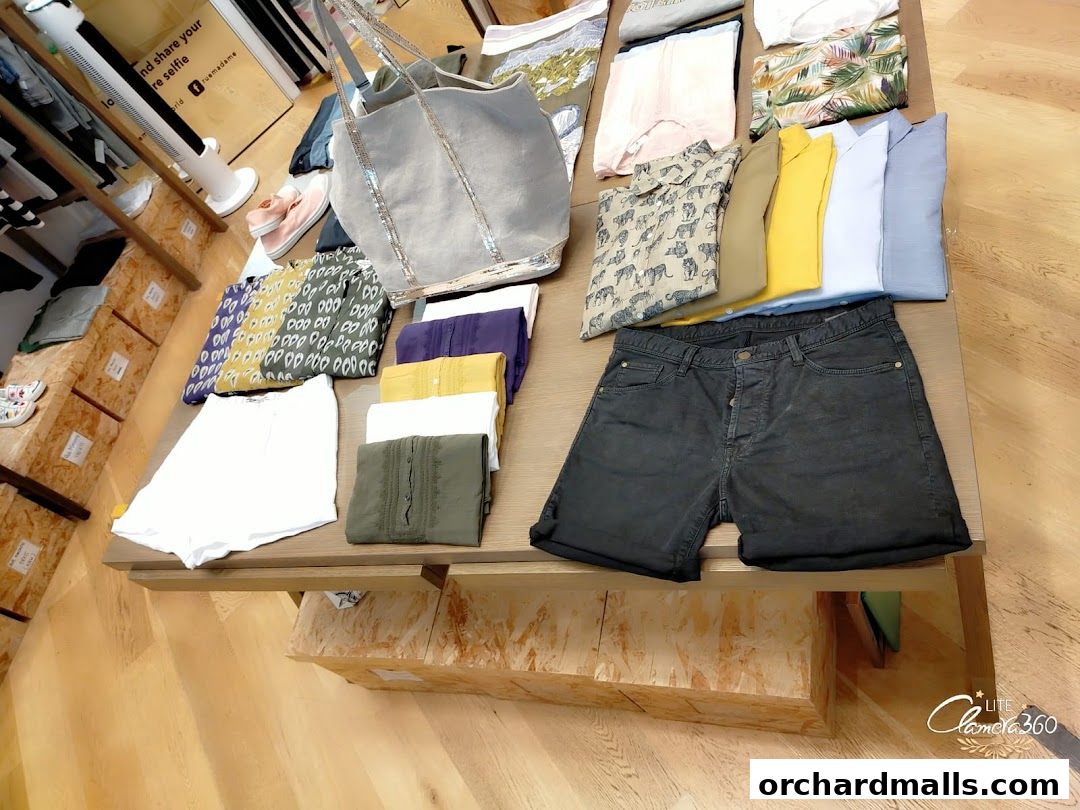 A display of folded clothing items and a tote bag on a wooden table.