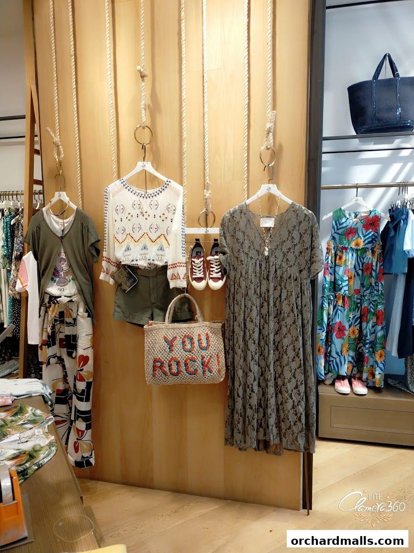 Fashionable clothing and accessories displayed on wooden mannequins and racks.