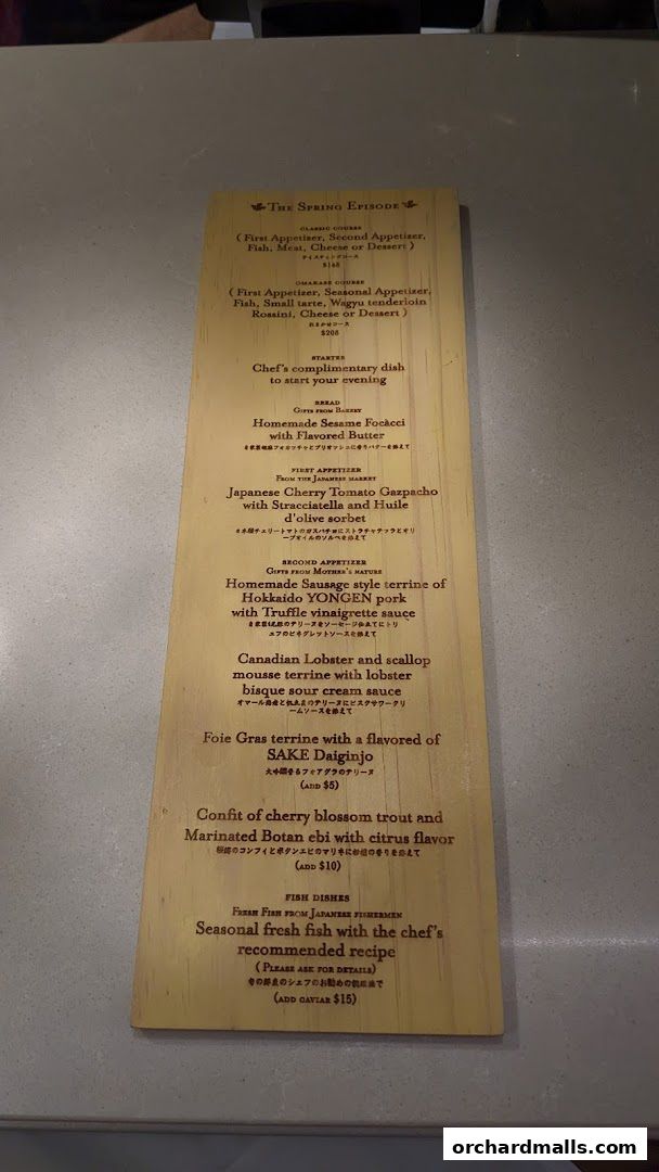 A wooden menu board with "The Spring Episode" and various course descriptions.