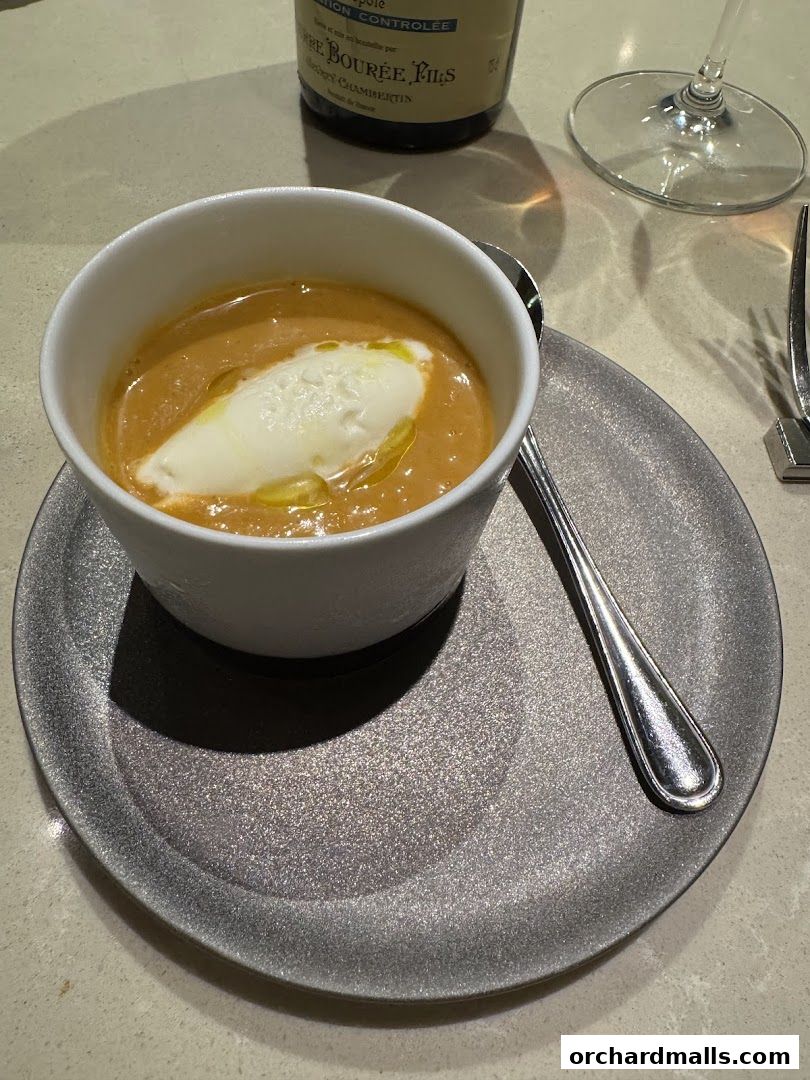 A bowl of creamy soup with a dollop of cream and a drizzle of olive oil.