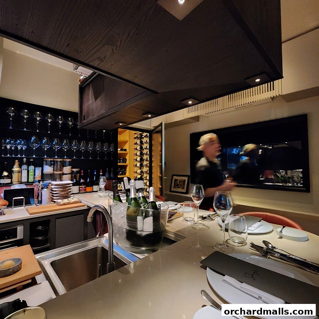 Interior view of a bar area with wine bottles, glasses, and a person in the background.
