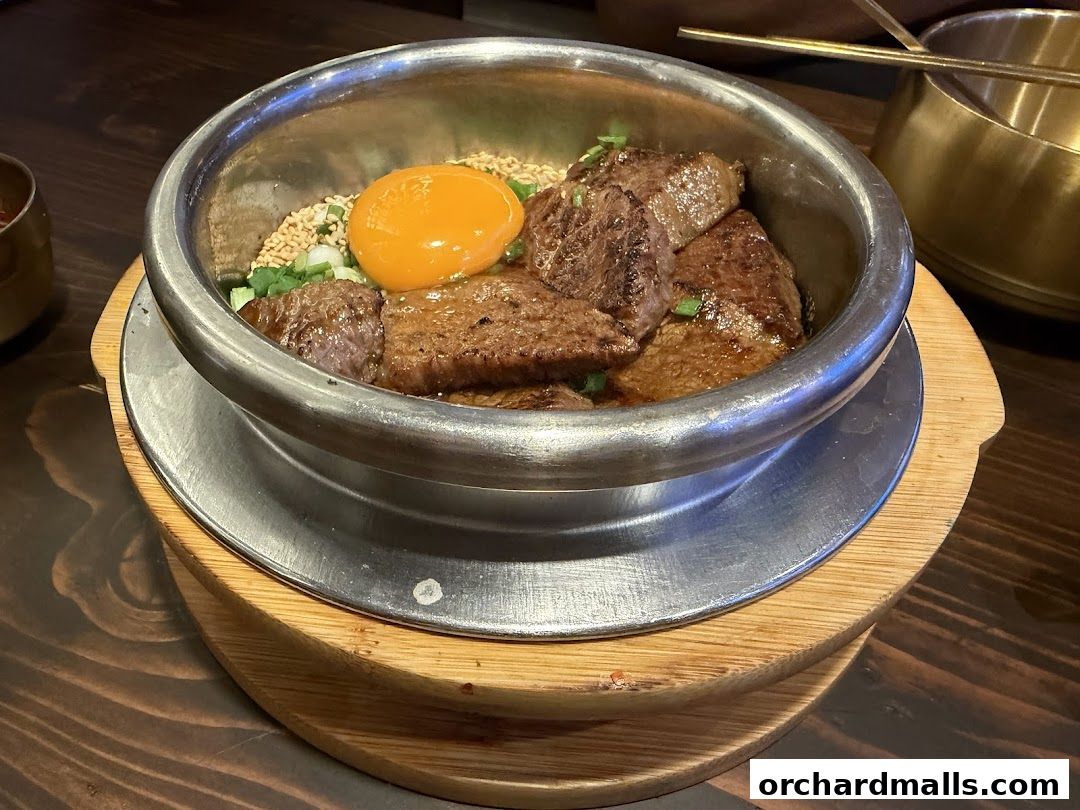 A close-up of a Korean pot rice dish with beef and a raw egg yolk.