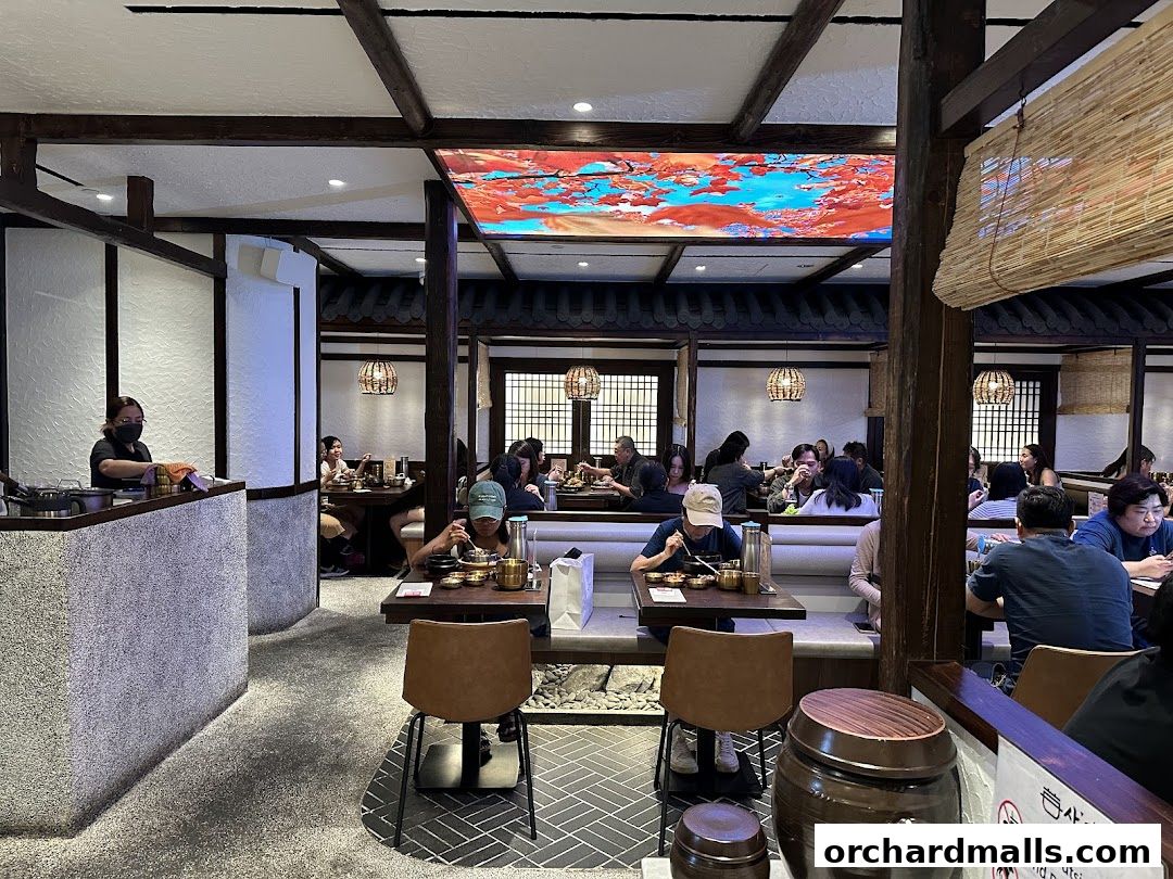 Diners enjoy Korean pot rice and BBQ in a restaurant with traditional decor.