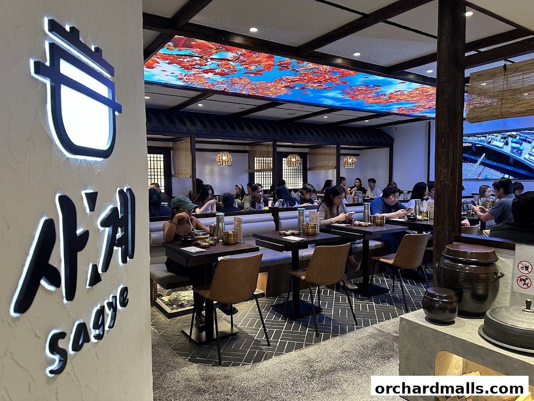 Interior of a Korean restaurant with diners at tables and decorative ceiling art.