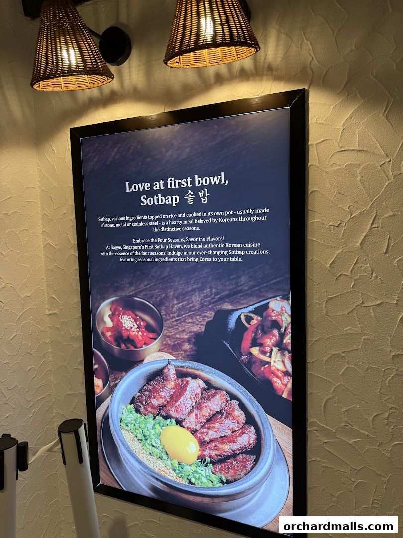 A framed advertisement showcasing a Korean dish called Sotbap with accompanying side dishes.