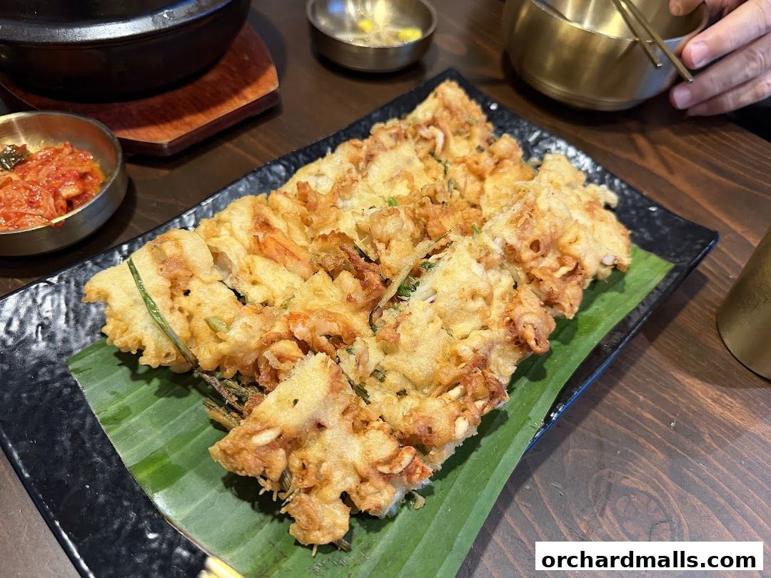 A plate of Korean seafood pancake served with kimchi and other side dishes.