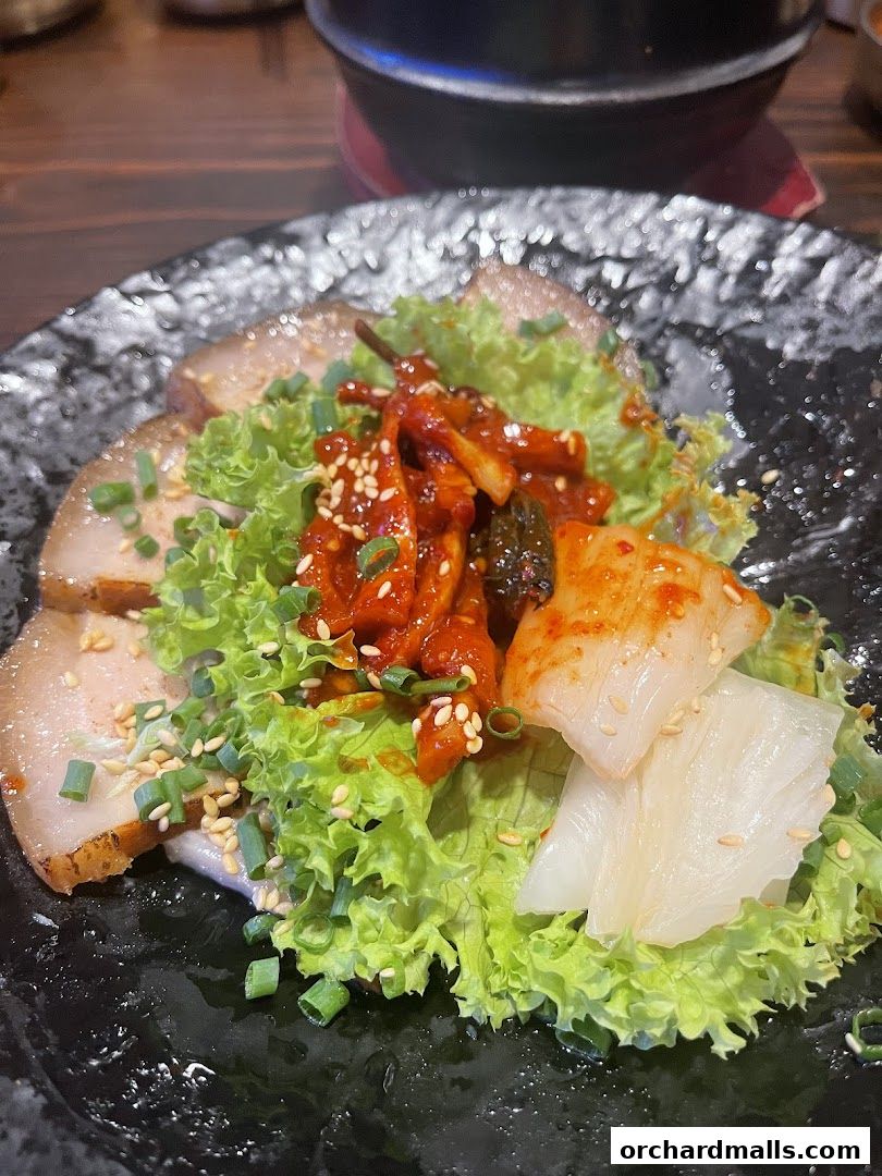 A close-up of Korean pot rice and BBQ dish with pork, kimchi, and lettuce.
