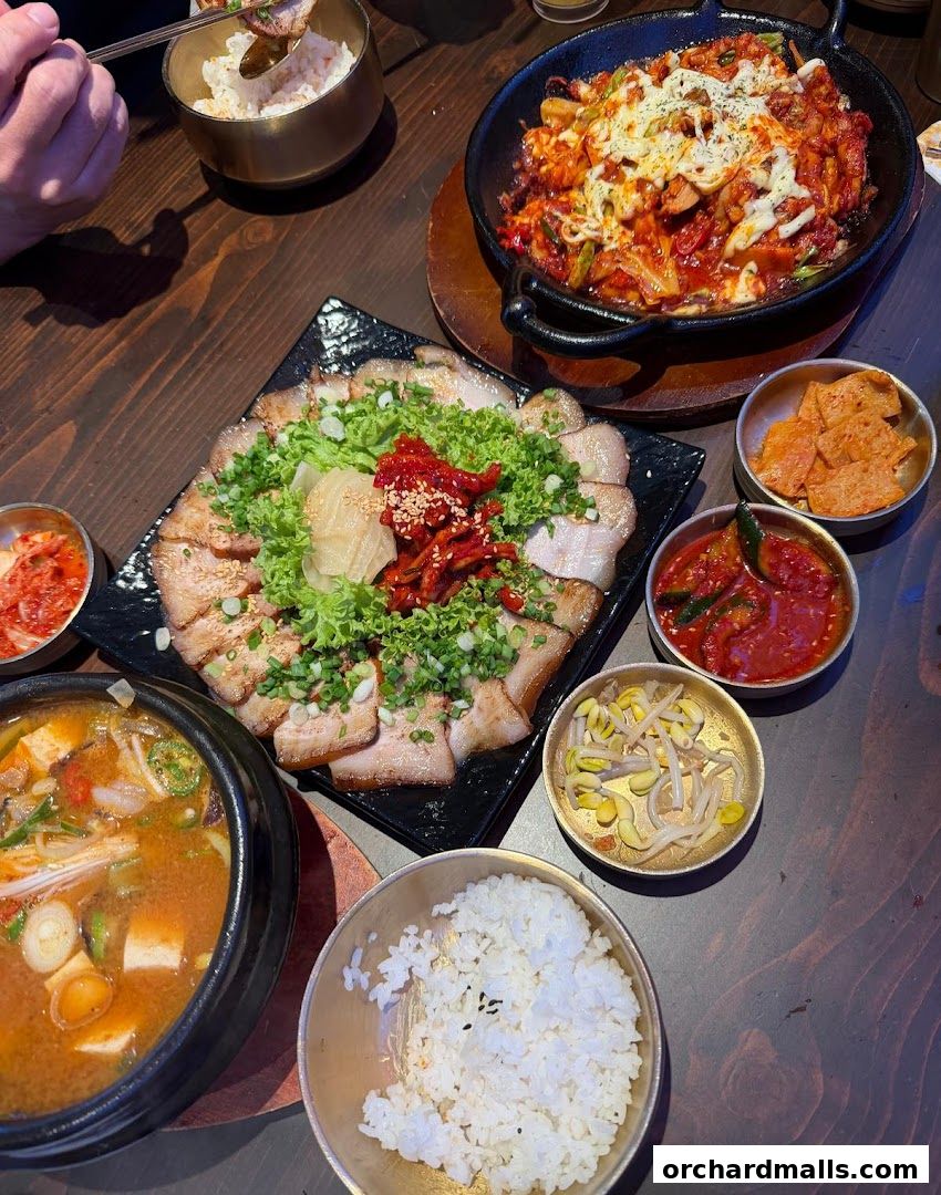 A spread of Korean dishes including pork belly, stew, rice, and kimchi.