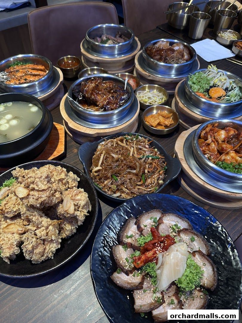 A table laden with various Korean dishes, including BBQ, fried chicken, and soup.