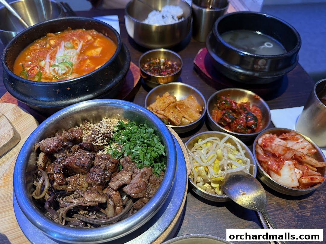 A table laden with Korean dishes including kimchi, rice, soup, and grilled meat.