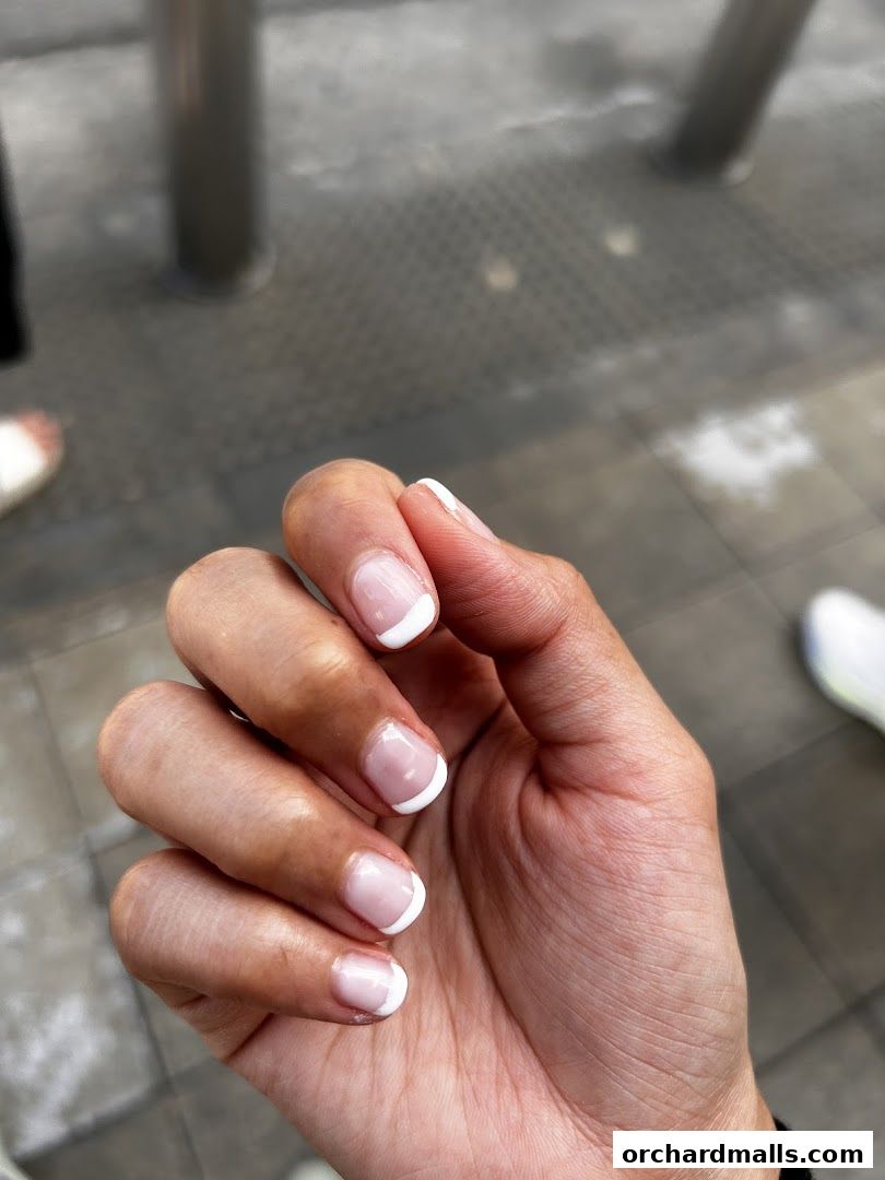 A close-up of a hand with perfectly manicured French tip nails.