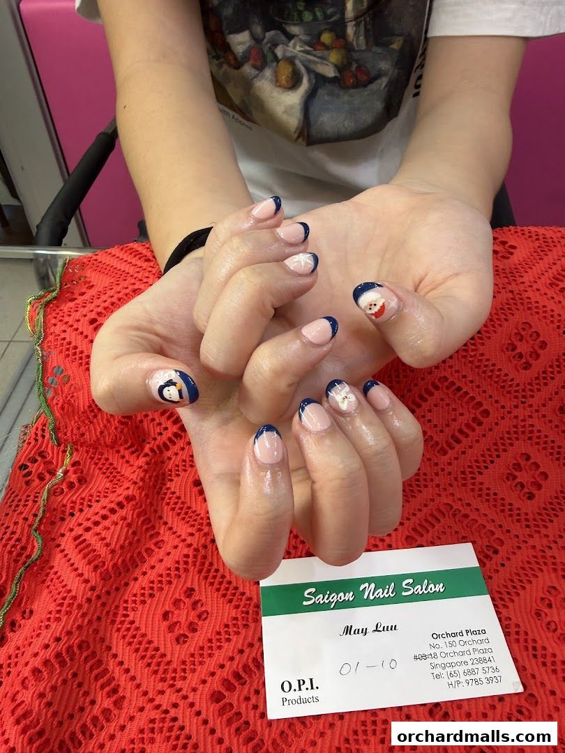 A person displays festive Christmas-themed French manicures with Santa and snowflake designs.