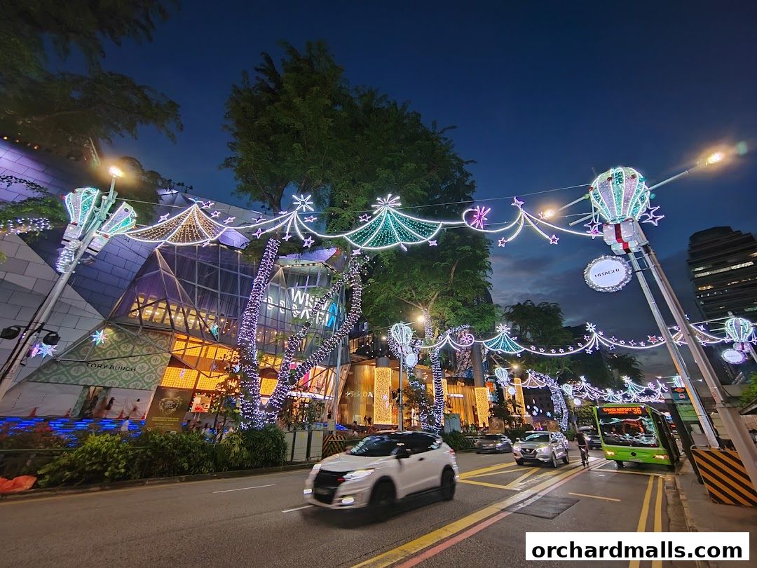 A street view of a modern building adorned with festive Christmas lights at dusk.