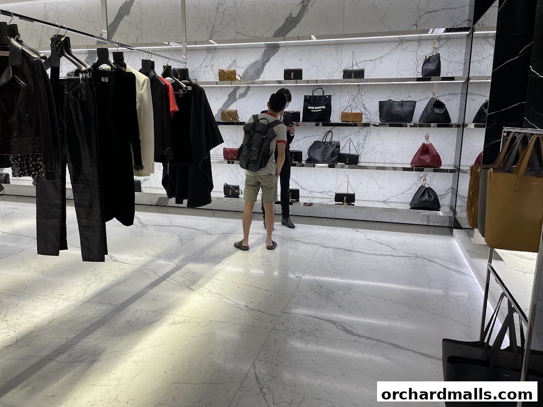Interior of a Saint Laurent store showcasing handbags and clothing on display shelves and racks.