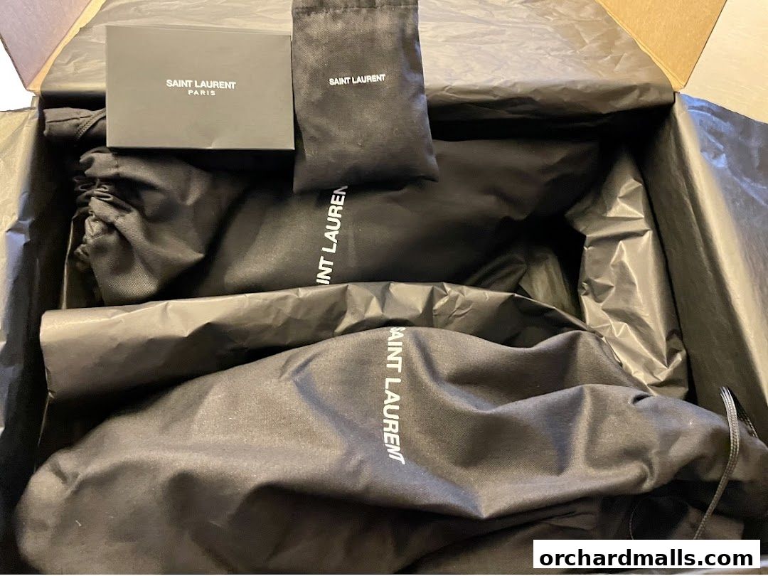 A Saint Laurent branded box containing items in protective dust bags.