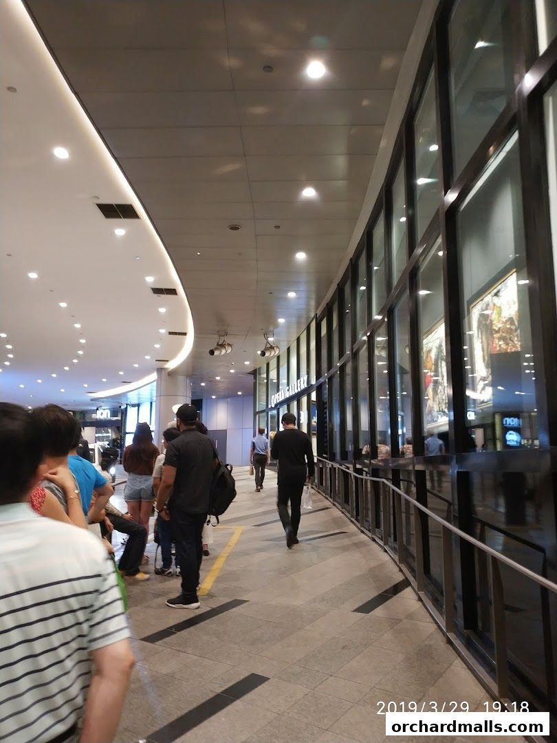 People walking in a modern shopping mall with a Saint Laurent store visible.