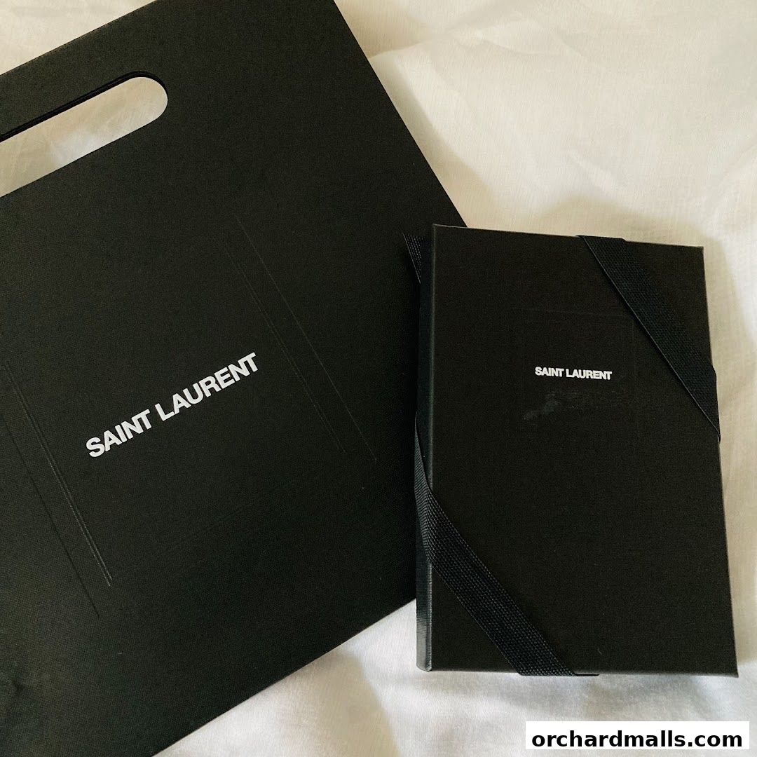 A black Saint Laurent shopping bag and a black Saint Laurent notebook with elastic closure.