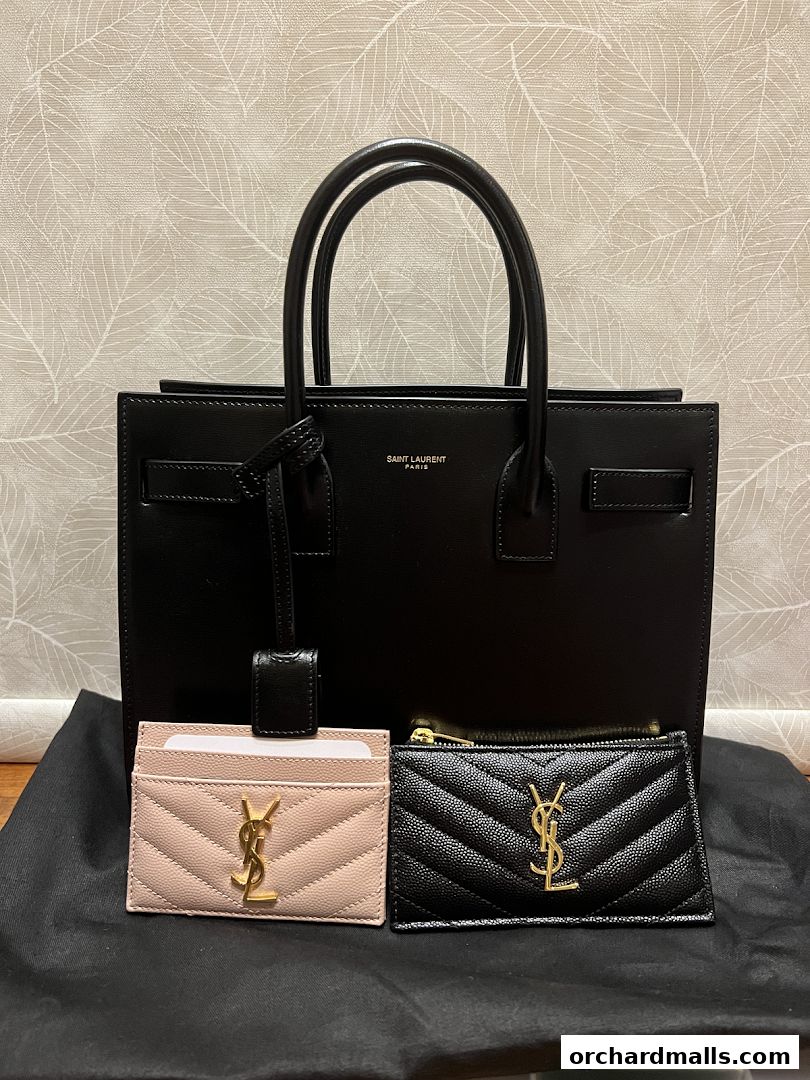 A black Saint Laurent handbag with a pink and black cardholder.