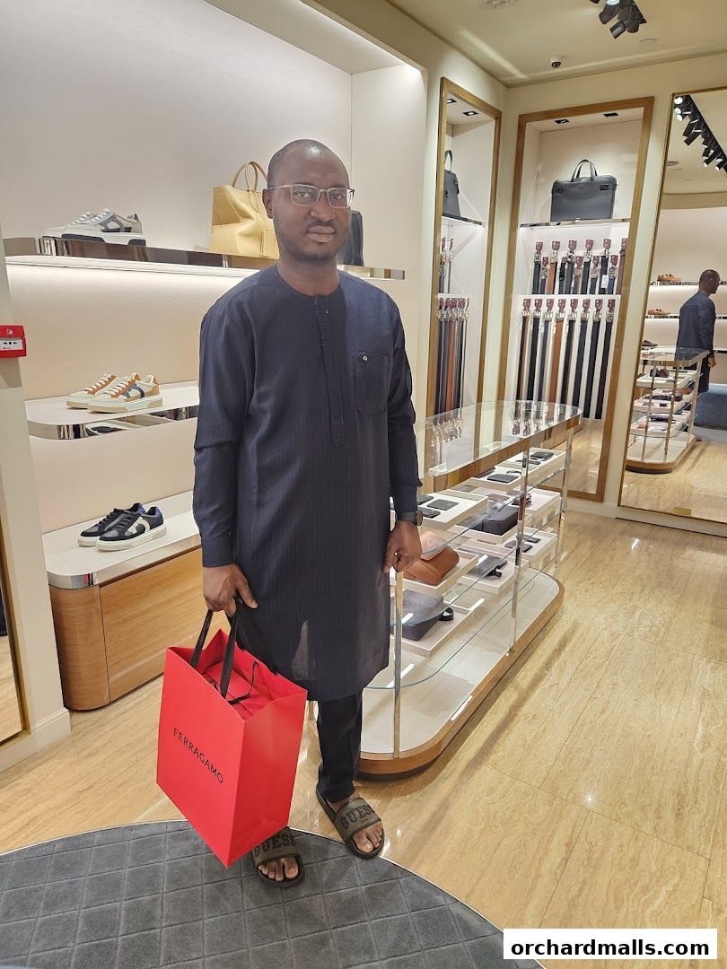 A man stands in a Salvatore Ferragamo store holding a red shopping bag.