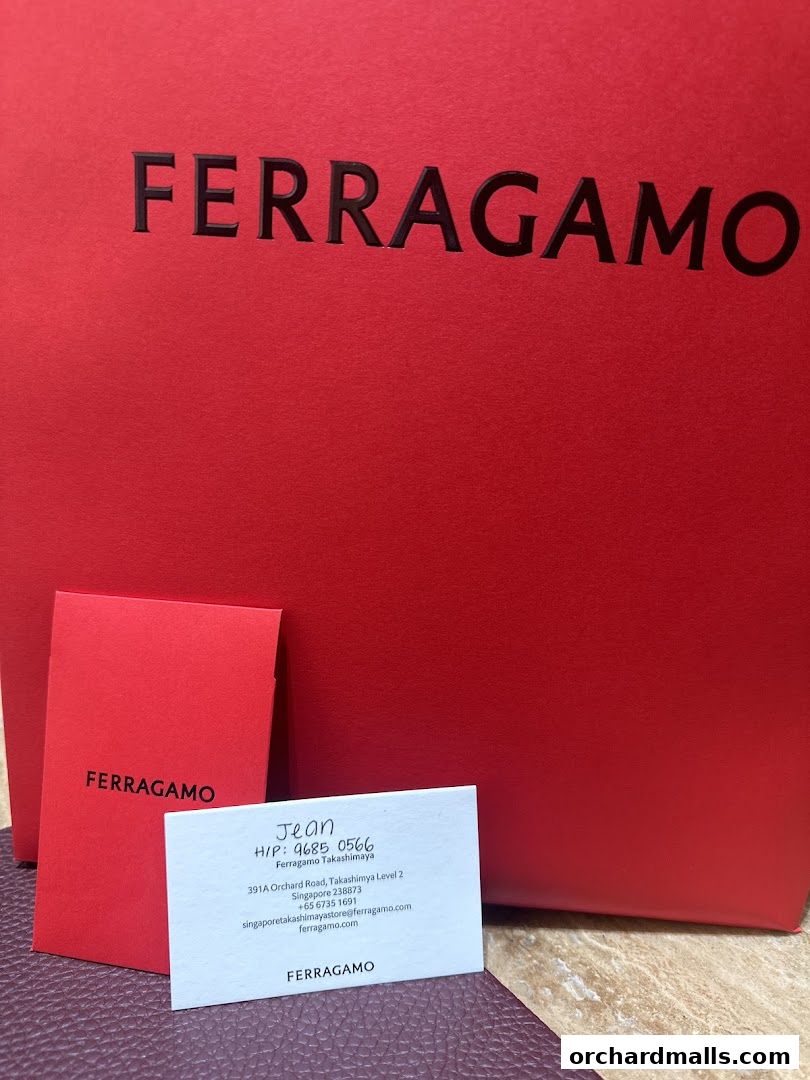 A red Salvatore Ferragamo shopping bag with a business card and a small red card.