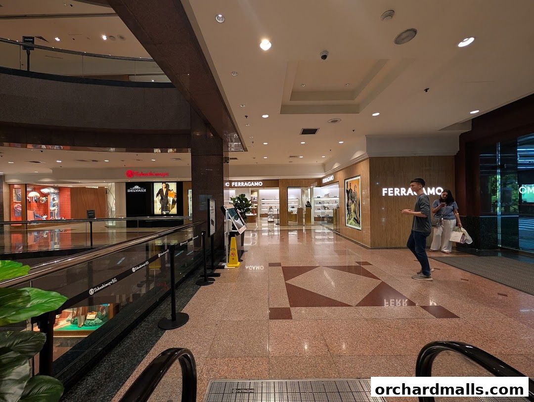 Interior view of a shopping mall with Salvatore Ferragamo and other luxury stores visible.