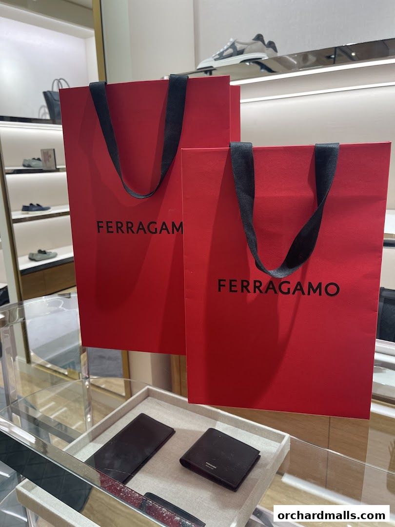 Red Salvatore Ferragamo shopping bags and wallets displayed in a luxury retail store.