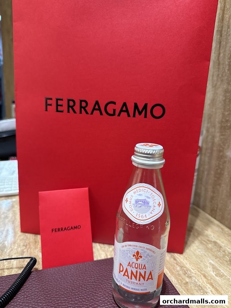 A red Salvatore Ferragamo shopping bag with a bottle of Acqua Panna water.