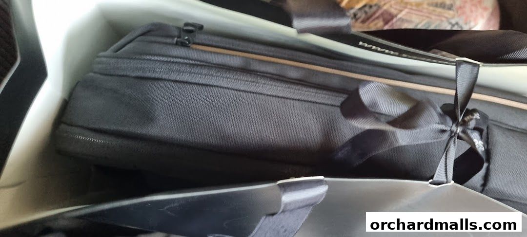 A close-up shot of a black Samsonite bag with a ribbon tied around its handle, inside a shopping bag.