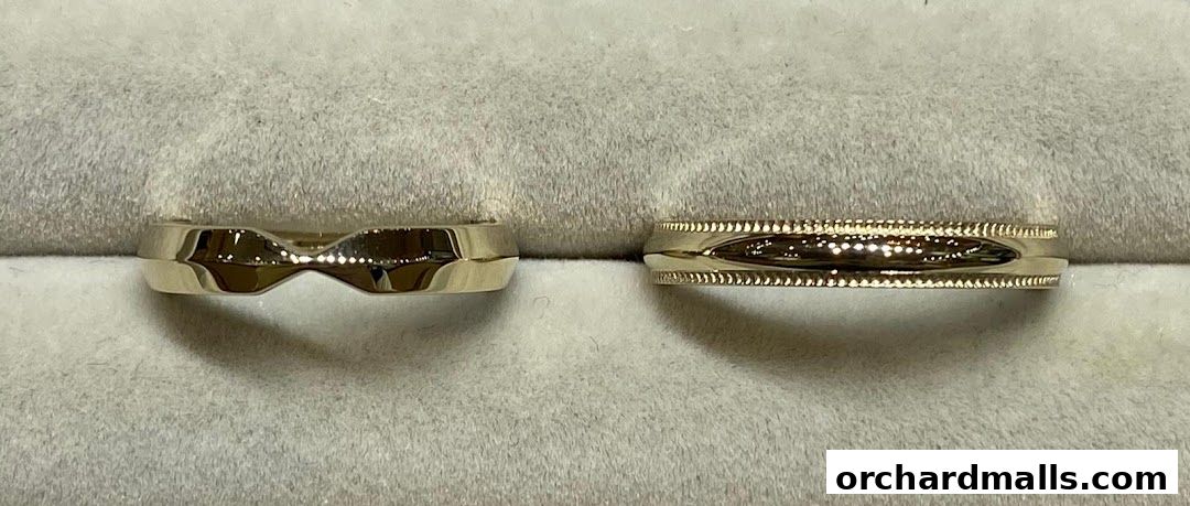 Close-up view of two elegant gold rings displayed on a soft, grey surface.