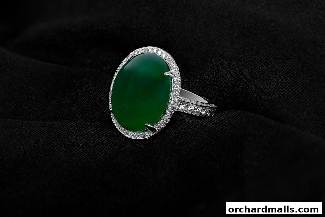 A stunning oval green gemstone ring with diamond accents on a black fabric background.