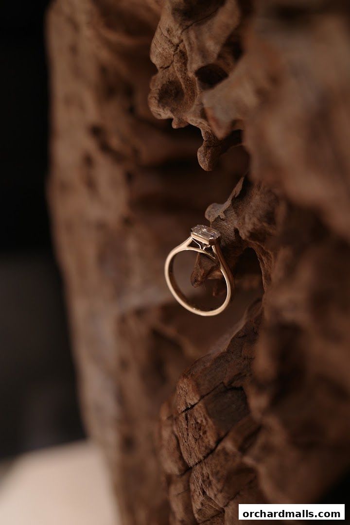 A gold ring with a diamond rests on a piece of weathered wood.