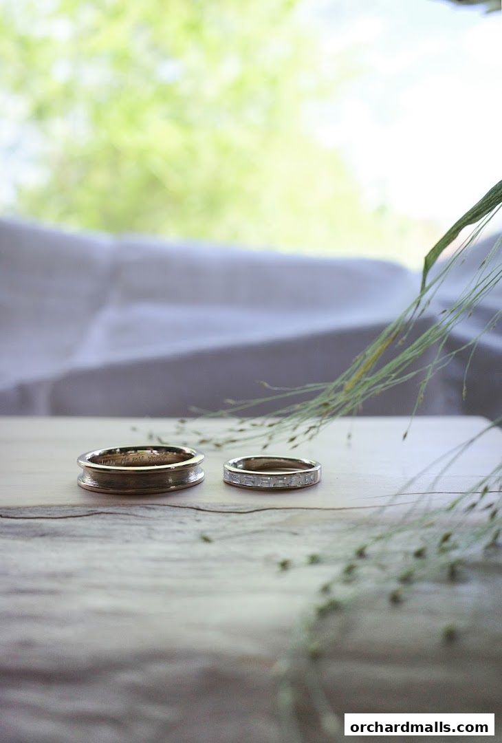 Two elegant rings, one plain and one with baguette diamonds, displayed on a wooden surface.