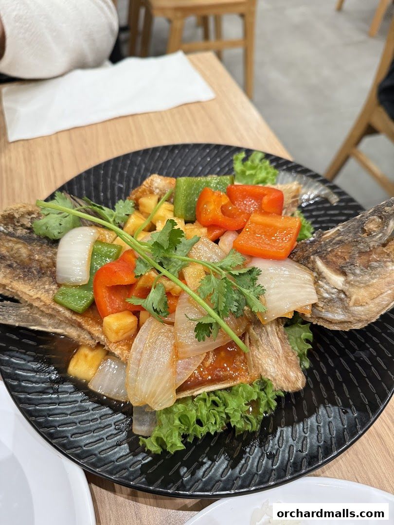A plate of Thai sweet and sour fish with vegetables and pineapple.