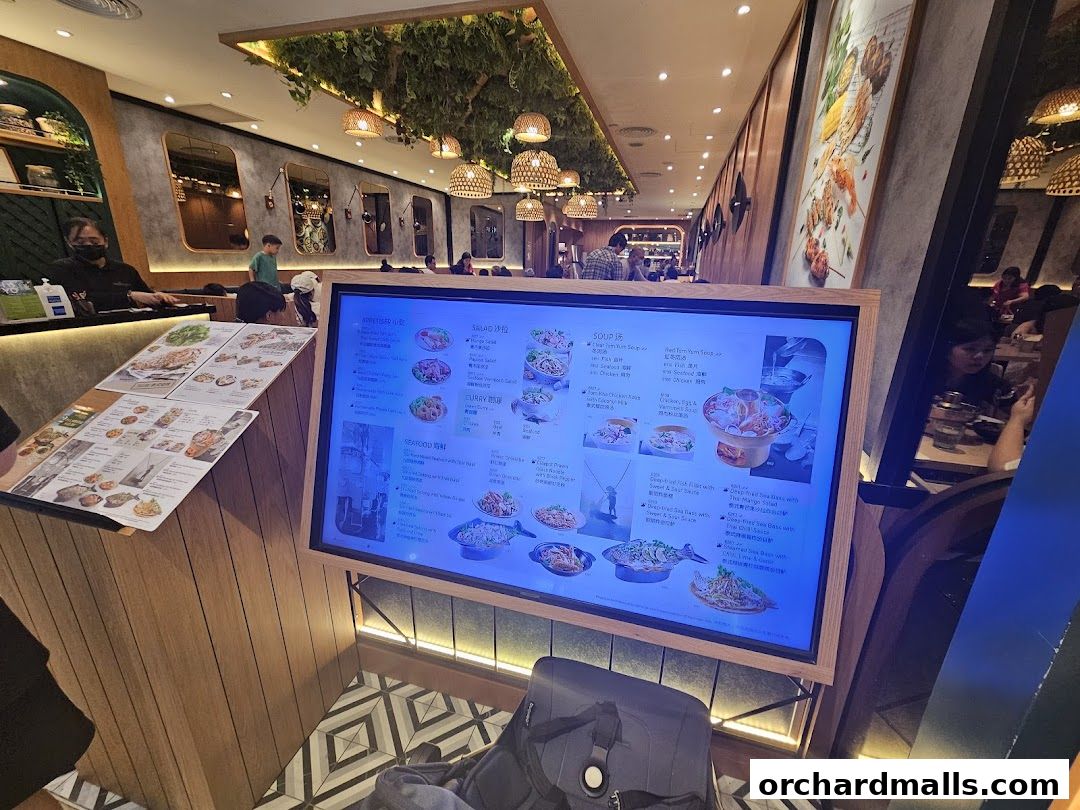 A digital menu board displays Thai dishes with images and descriptions.