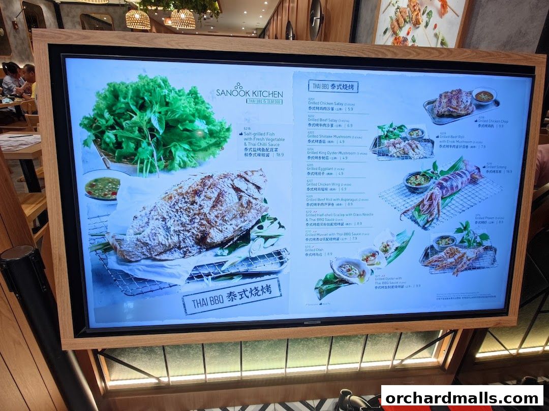 A digital menu board displaying various Thai BBQ and seafood dishes with images and prices.