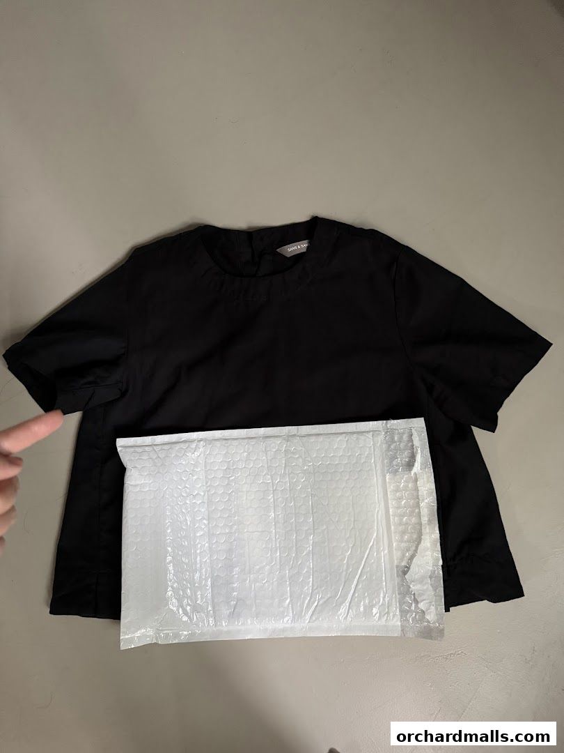 A black top from SANS SANS TAKASHIMAYA is laid out with a padded envelope.