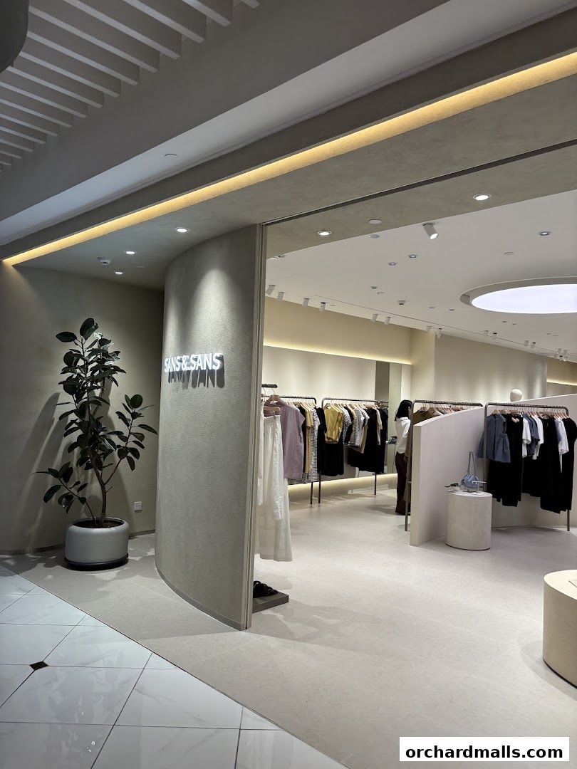 Entrance to SANS SANS TAKASHIMAYA clothing store with apparel displayed on racks.