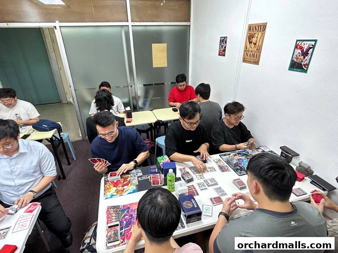 People playing card games at tables in a room with anime posters on the wall.