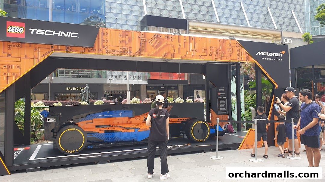 A life-size Lego Technic McLaren Formula 1 car display with onlookers.