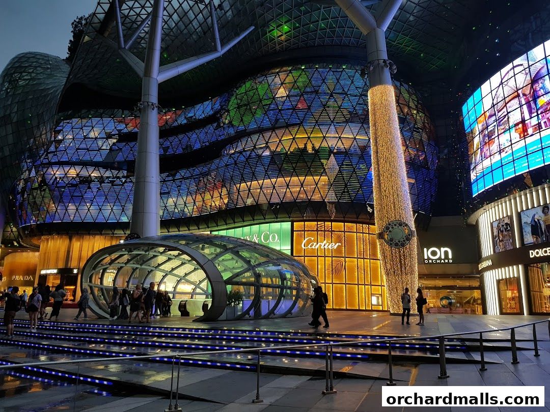 Exterior view of ION Orchard mall at night, featuring illuminated shops and architectural elements.