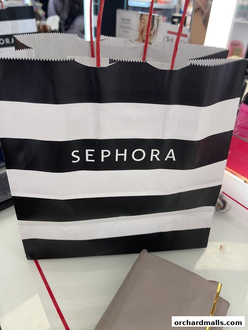 A black and white striped Sephora shopping bag with red handles.