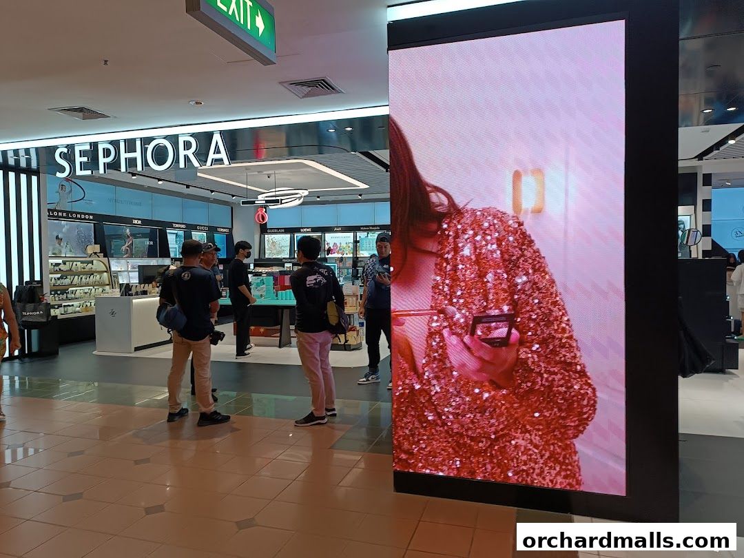 Sephora store interior with displays of beauty products and a large digital screen.