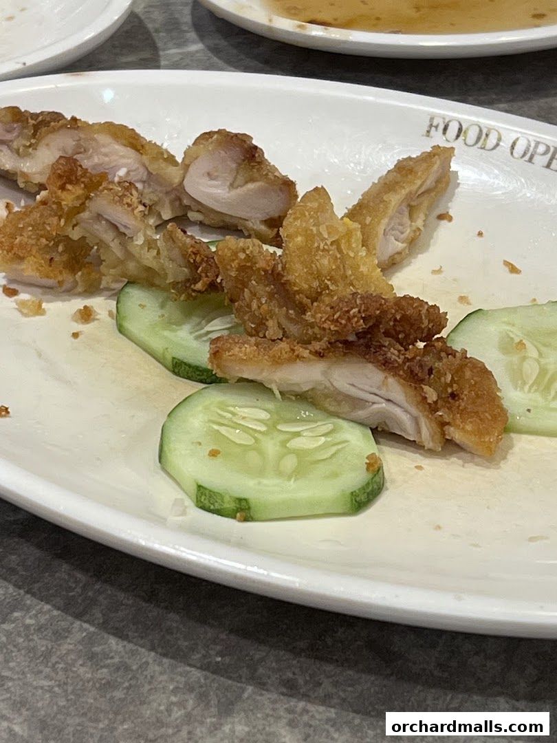 A plate of crispy fried chicken pieces served with cucumber slices.